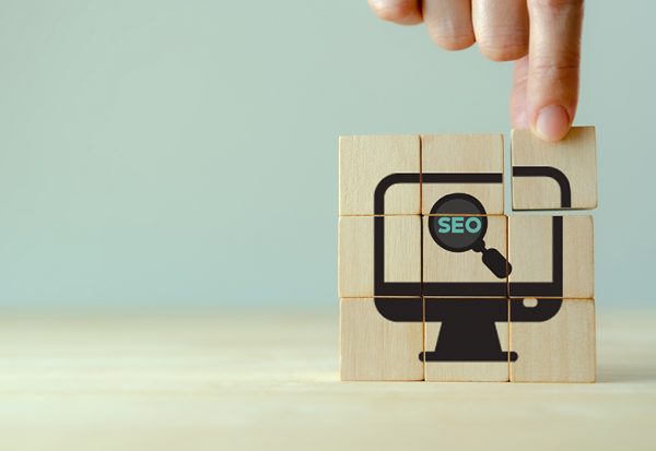 SEO, Search Engine Optimization ranking concept.  Digital marketing strategy of promote traffic to website. Hand holds wooden cubes with the icon of magnifying glass with alphabets abbreviation SEO.